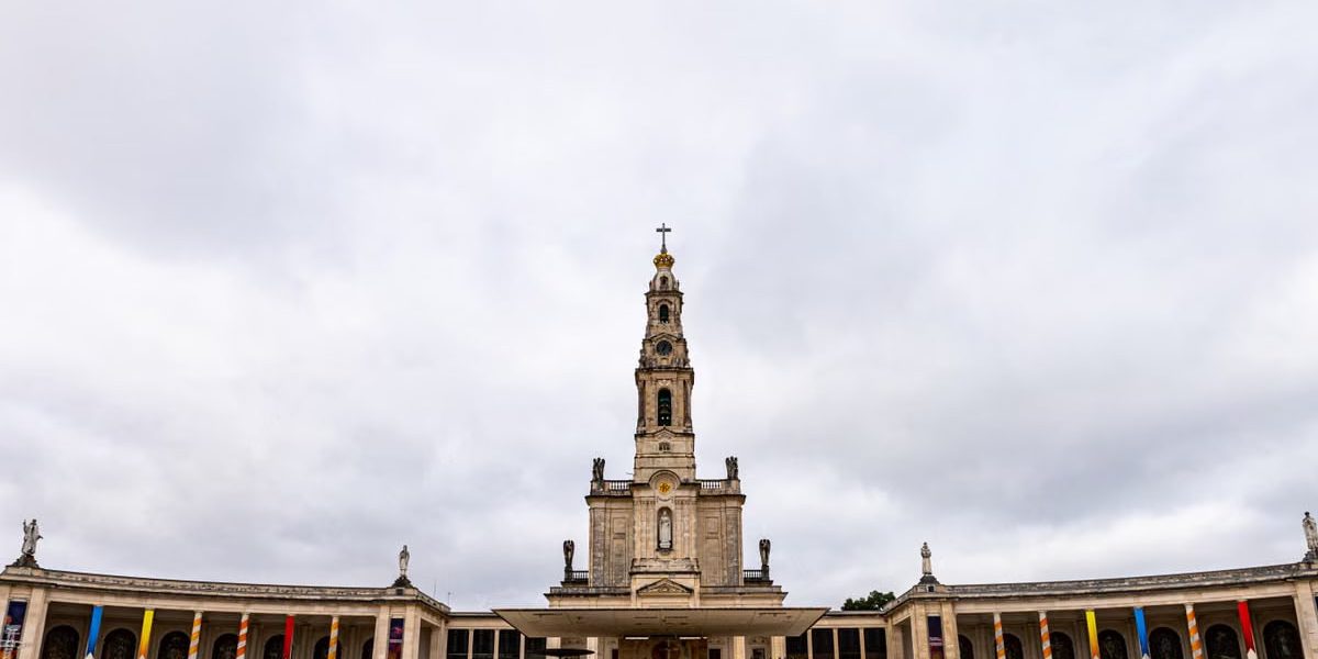 A view of the Sanctuary of Fátima in Portugal under a cloudy sky, highlighting its architectural beauty.