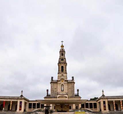 A view of the Sanctuary of Fátima in Portugal under a cloudy sky, highlighting its architectural beauty.